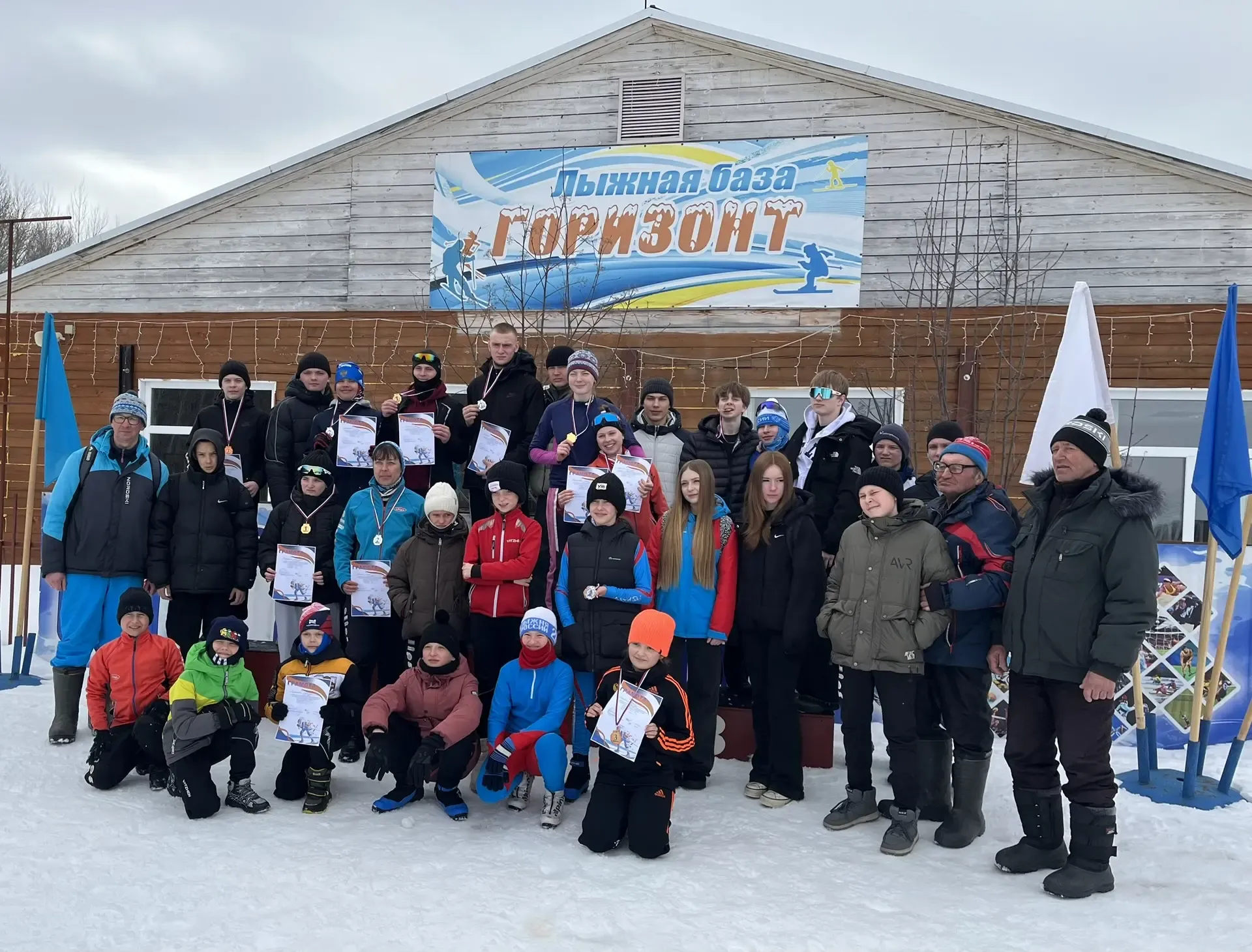 Групповое фото участников и призёров лыжных соревнований на базе «Горизонт» в Барабинском районе, награждение спортсменов с дипломами и медалями зимой